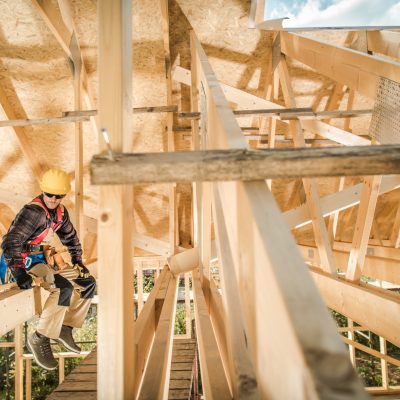 Construction Worker Sitting on a Wooden Roof Beam